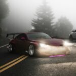 Red sports car with headlights on, driving through a foggy mountain road with pine trees.